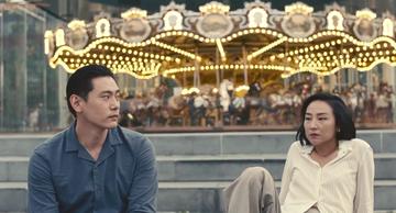 Past Lives_Nora and Hae Sung by the carousel